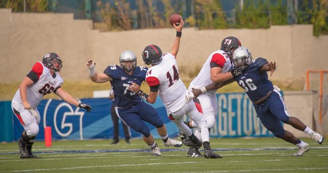 Davidson quarterback Stockton McGuire (14) is pressured by Hoyas' Brennen Sawicki (79) and Mike Taylor III (36)